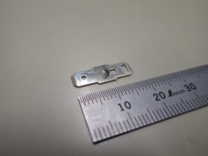 C2680R-1/4H-SM（t=0.5mm）の黄銅を用いた家電端子部品の順送プレス加工サンプル。カットベンドを伴う鋭角曲げ部の亀裂を、金型内の条件微調整と当たりの最適化によって抑制し、量産での安定性を確保した製品写真。