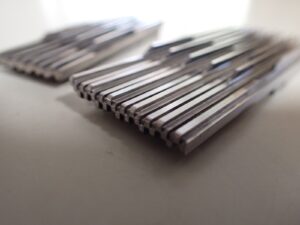 精密加工で仕上げた超硬製の櫛歯状金型部品。細い歯が等間隔に並ぶ