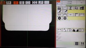 プロファイル研削盤のCCDカメラ画面。加工部の輪郭を拡大表示し、十字線で位置を合わせながら研削する
